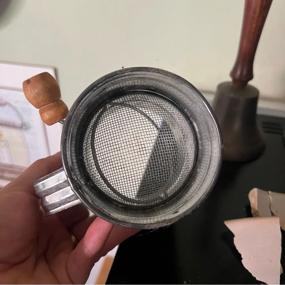 Antique, aluminum sifter with wooden handle.